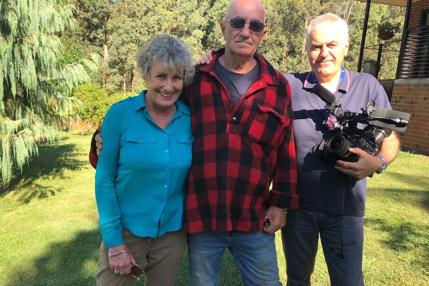 Ewart, Guilfoyle and Tucci holding camera posing for camera with bush in background.