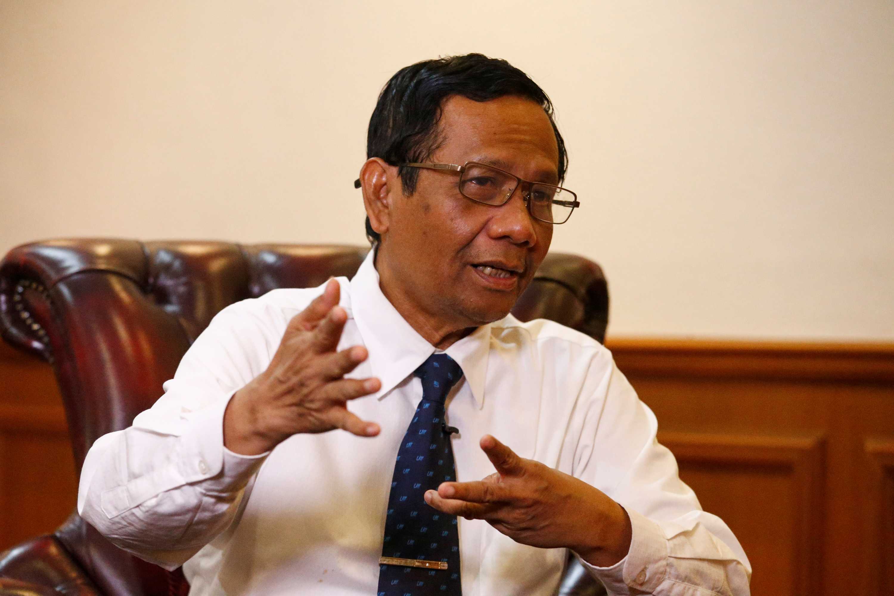 Indonesian man in white shirt and blue tie gestures with his hands as he speaks.