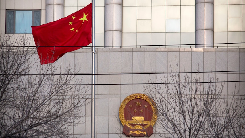 A Chinese flag flies in front of a courthouse in China.