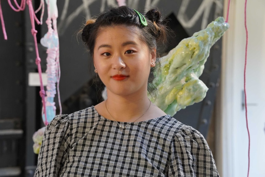 A woman standing in front of colourful artwork.