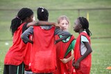 Girls huddled together on their soccer field.