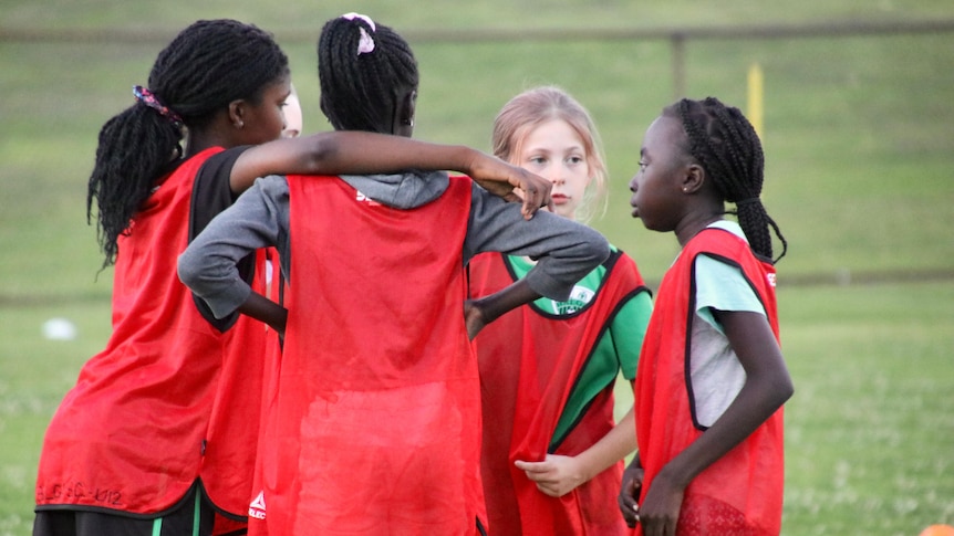 Girls huddled together on their soccer field.