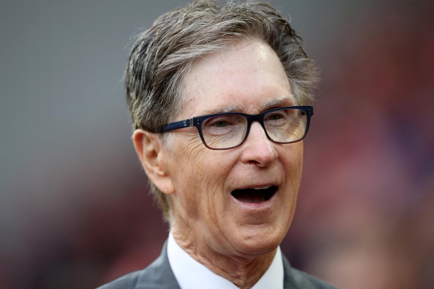 Un John Henry con gafas sonríe con la boca abierta 