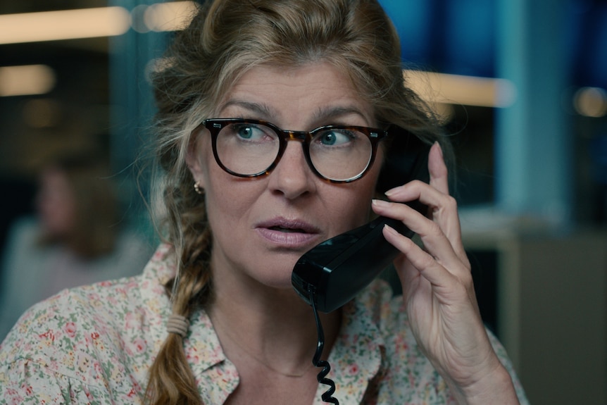 Movie still: Woman looks concerned talking on phone.