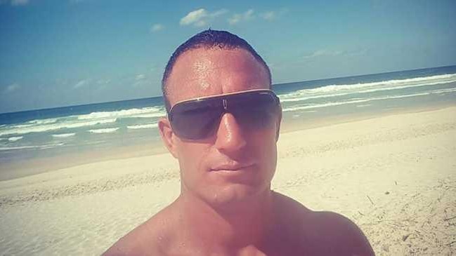 Dru Baggaley takes a selfie while wearing sunglasses on a beach.