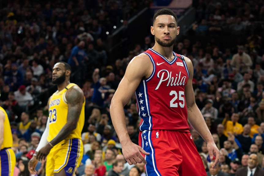 Ben Simmons is mean-mugging after a dunk. LeBron James looks frustrated behind him.