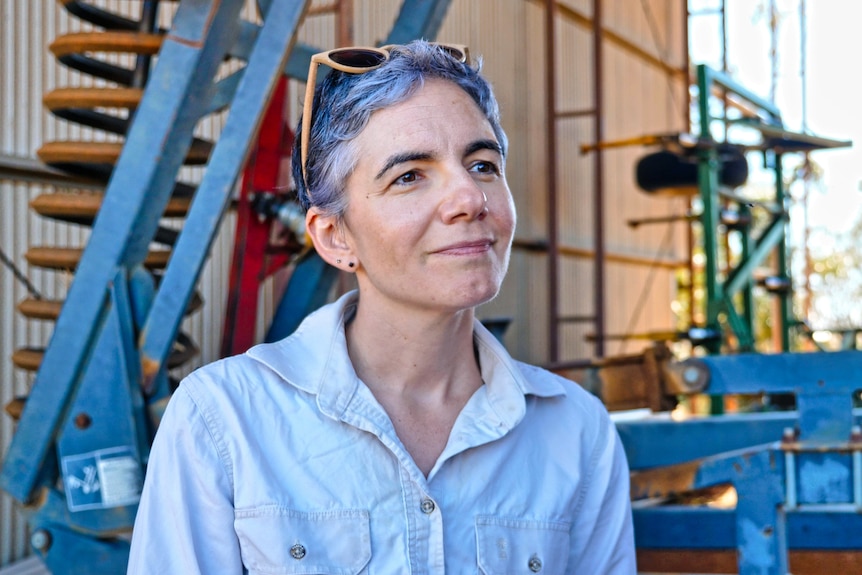 A head and shoulders shot of a woman in front of a shed on a farm.