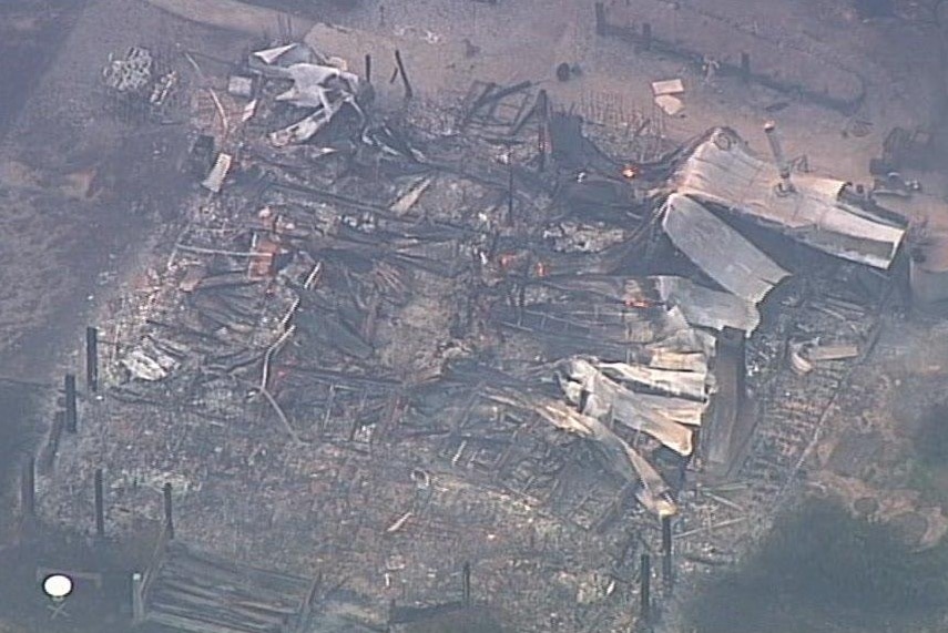An aerial shot shows burnt-out buildings blackened and destroyed by fire.