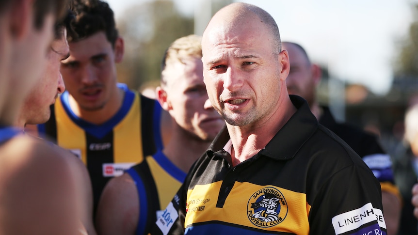 A VFL coach speaks to his players during a match in 2019.
