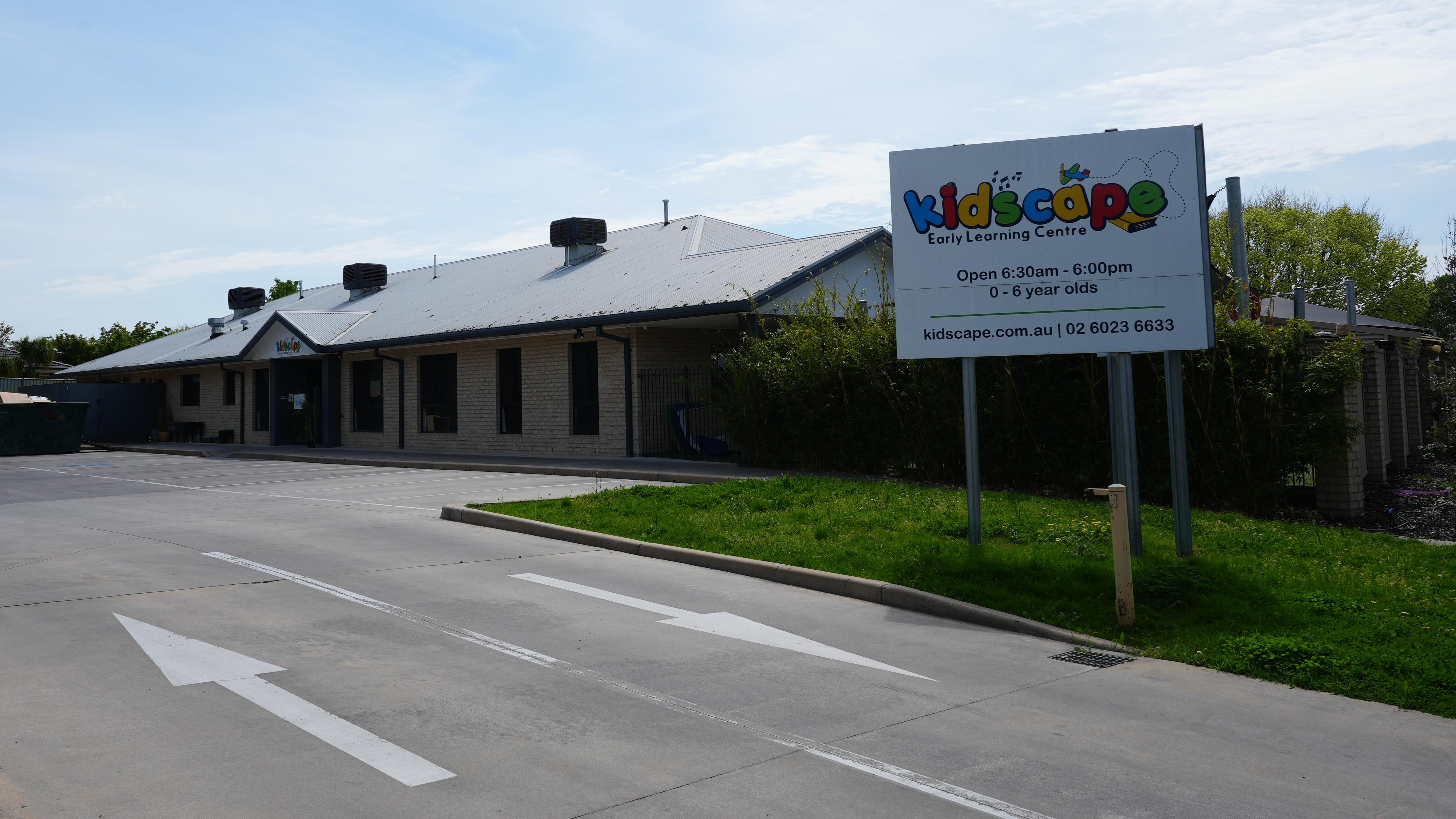 A sign for a childcare centre stands outside a single-story building.