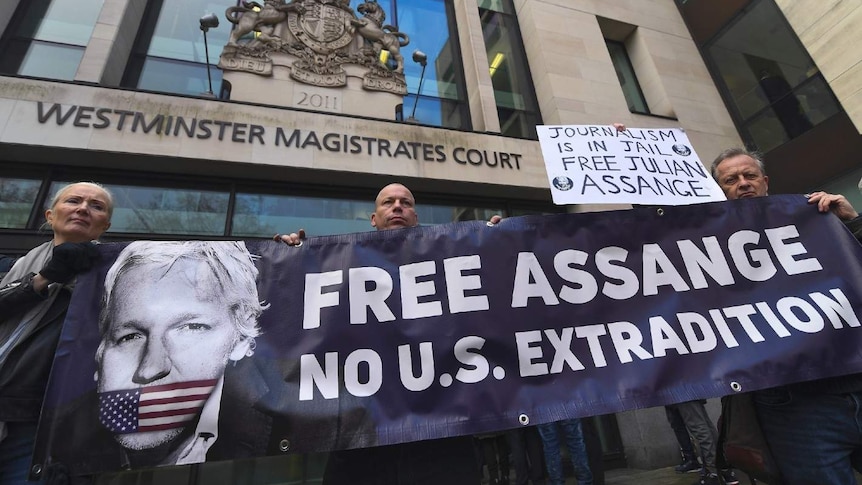 Three demonstrators hold up a banner that says "Free Assange. No U.S. extradition" outside Westminster Magistrates Court.