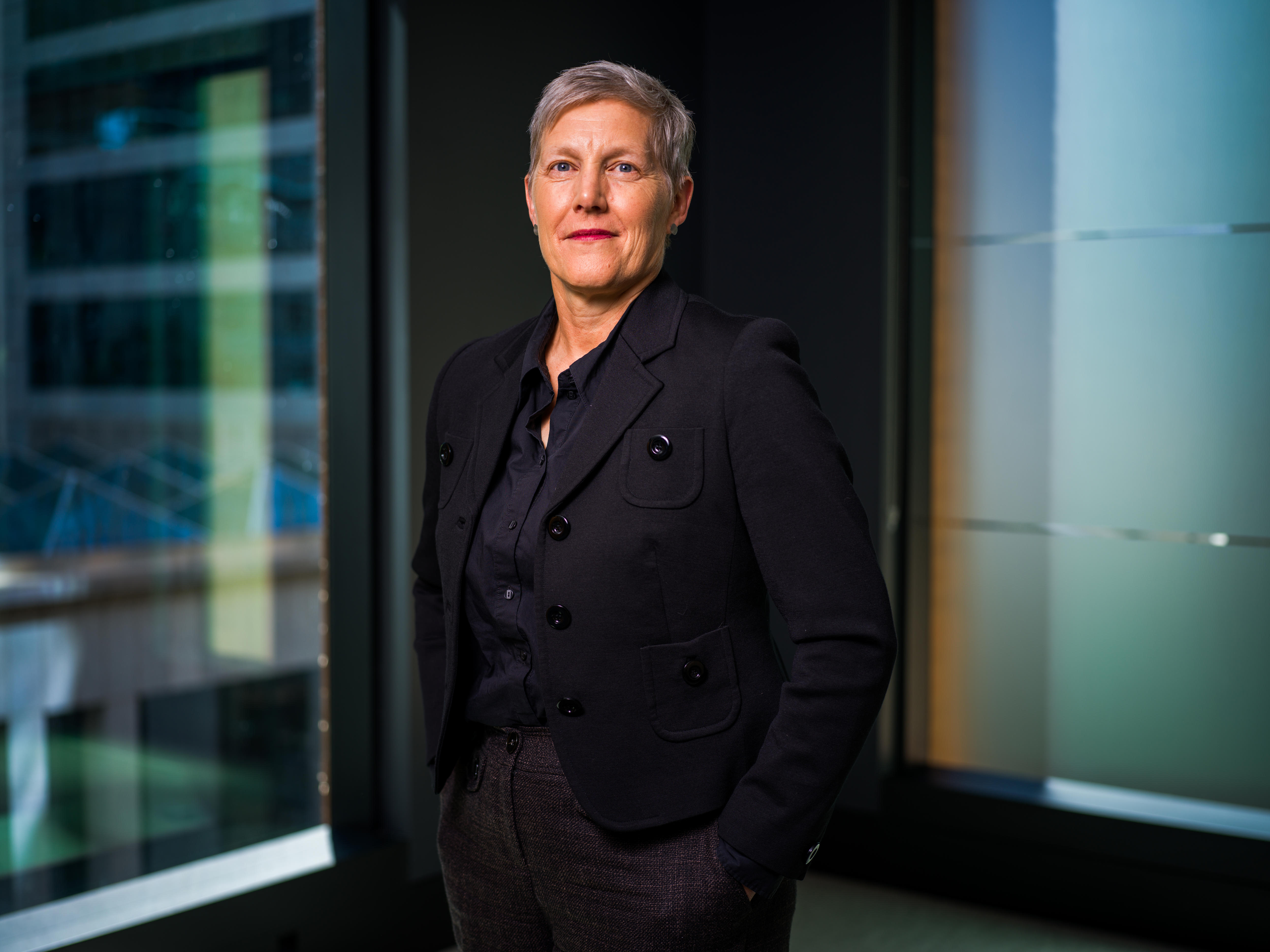A woman stands tall in a black suit.