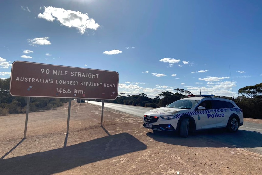 A police car sits parked across the Eyre Highway at the start of the Nullarbor Plain in WA.