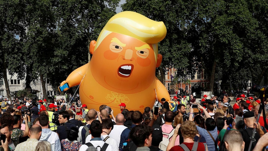 The orange inflatable balloon flies above a crowd outside parliament in London