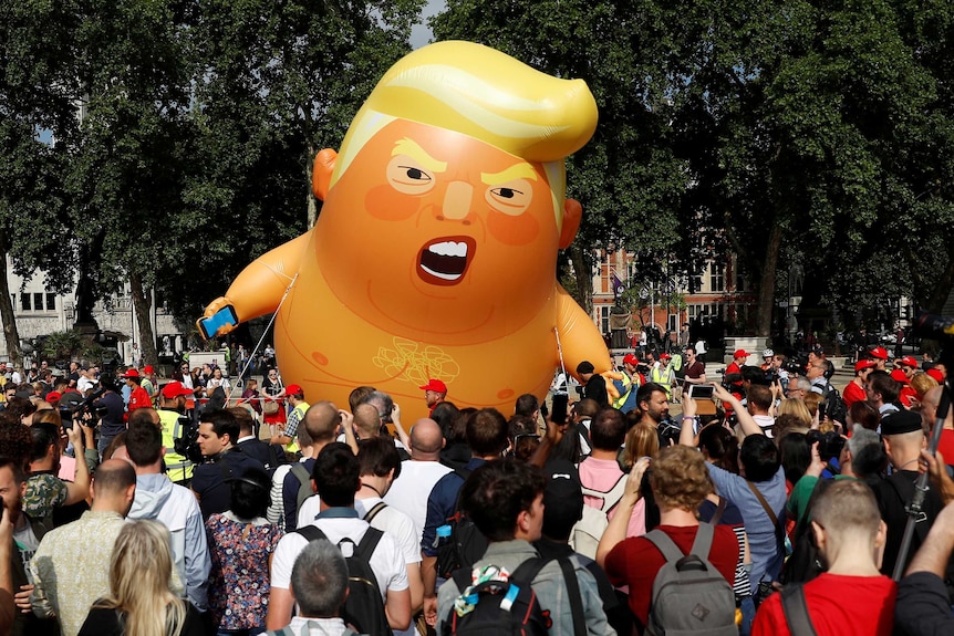 The orange inflatable balloon flies above a crowd outside parliament in London