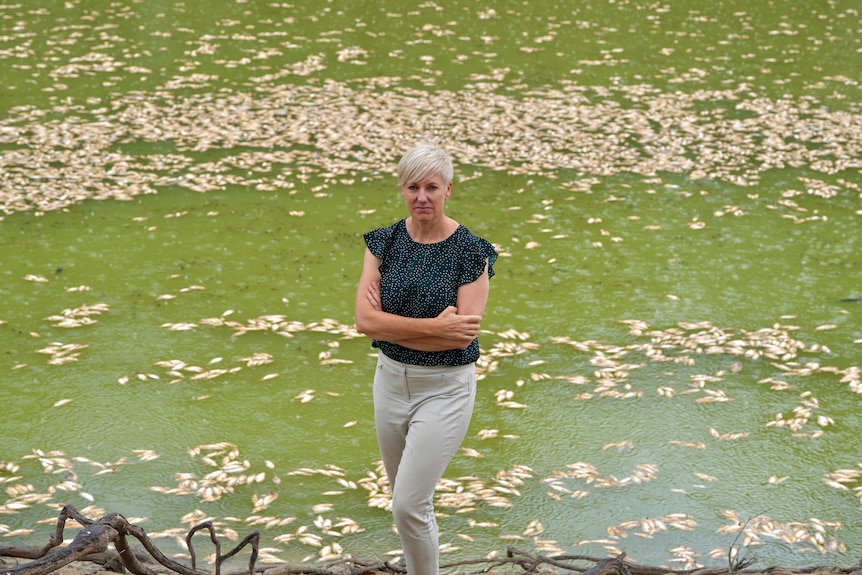 Silver-haired Greens MP Cate Faehrmann stands in front of the dead fish with her arms crossed.