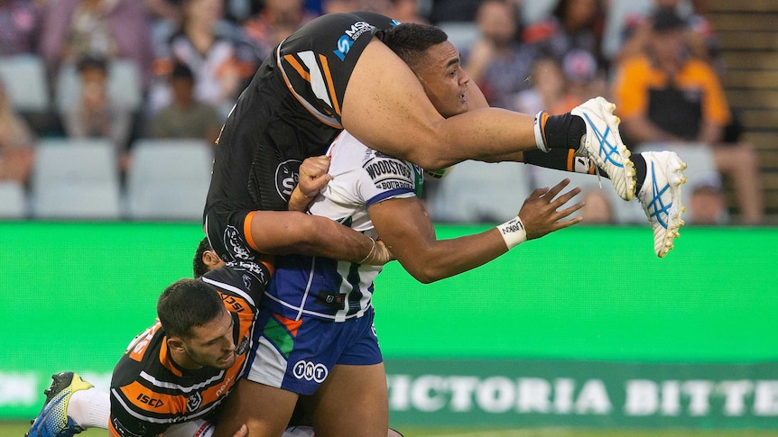 Elijah Taylor is upside down with his legs wrapped around Ken Maumalo's head, as Maumolo attempts to get off his knees