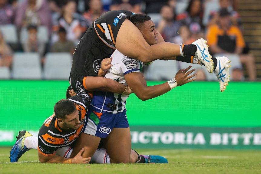 Elijah Taylor is upside down with his legs wrapped around Ken Maumalo's head, as Maumolo attempts to get off his knees