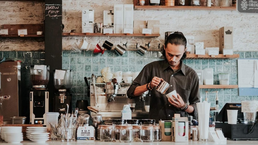 A barista pours a coffee in a rustic cafe.