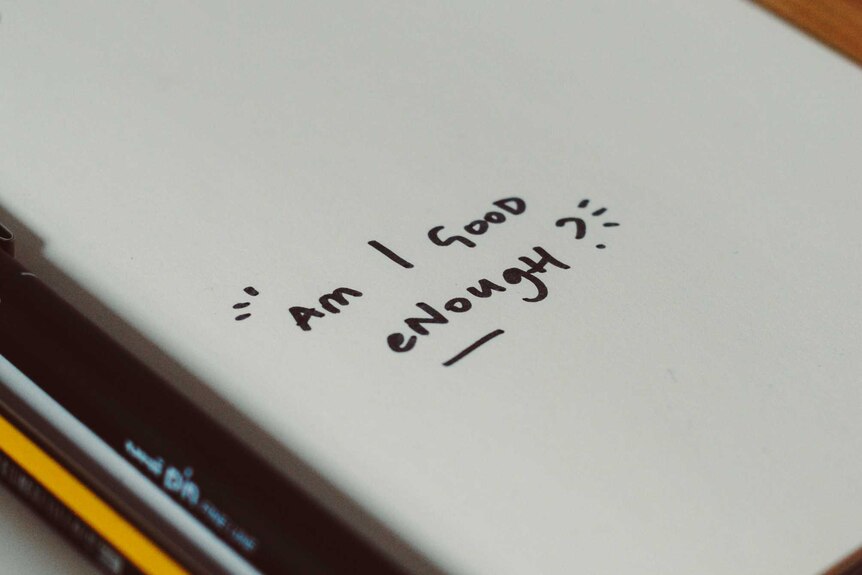 'Am I good enough?' handwritten on notebook