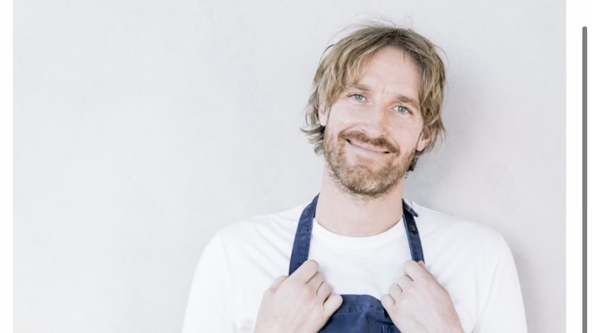 Smiling Chef Darren Robertson wearing blue apron.