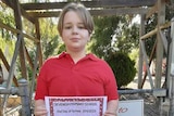 girl stands in front of school in red uniform 