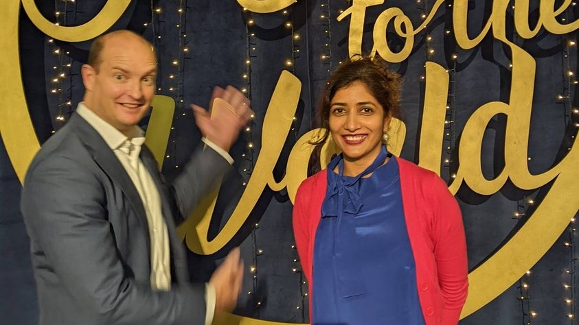 A man and a woman standing in front of a sign saying Joy to the World