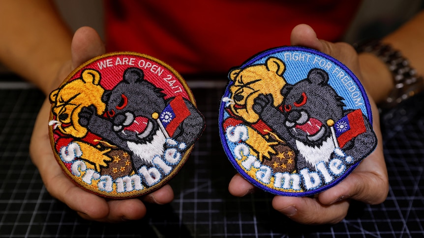 An up close photo of  two patches side by side, depicting a black bear holding Taiwan's flag and punching Winnie the Pooh.