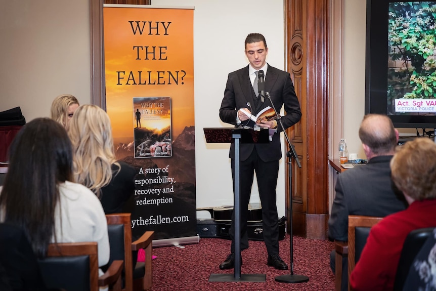 A man in a suit at a podium addressing a crowd