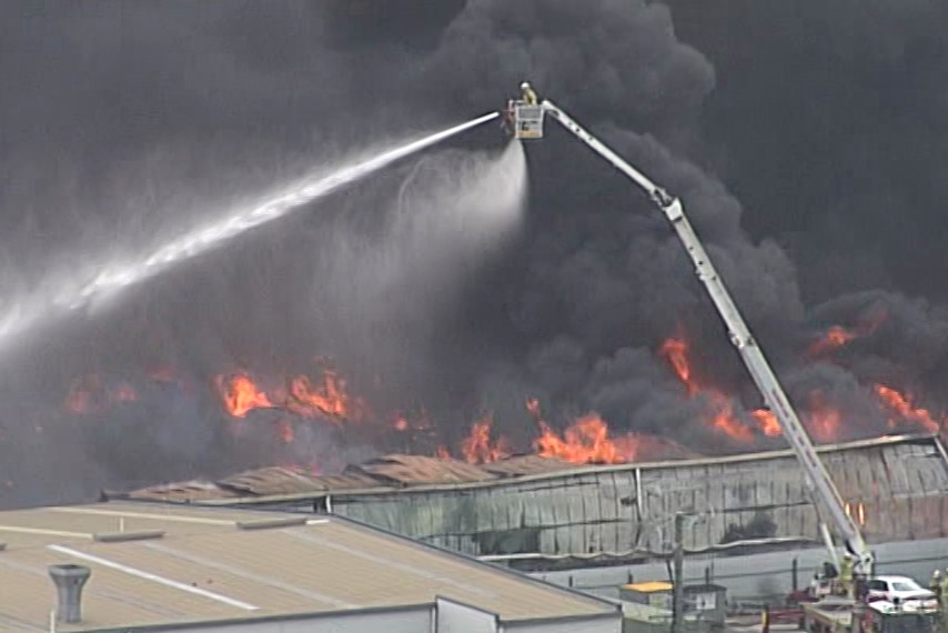 A firefighter hoses water on the fire from above.