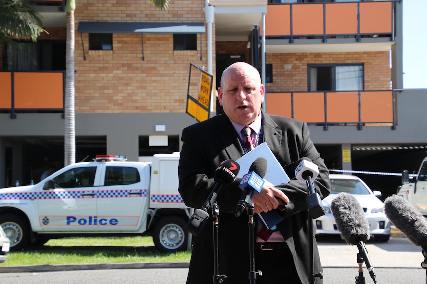 Andrew Massingham stands in front of media microphones across the road from the unit