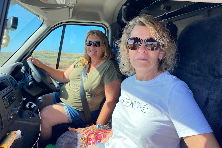 Two women pictured in a car with sunglasses on