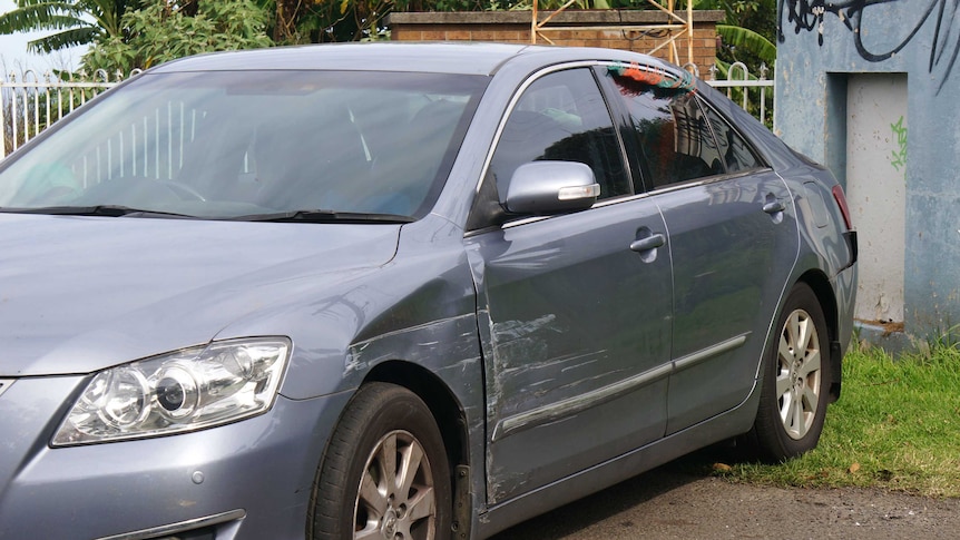 A grey-coloured sedan with scratches down the side.