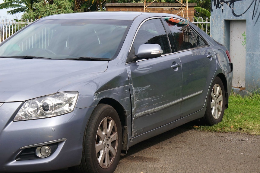 A grey-coloured sedan with scratches down the side.