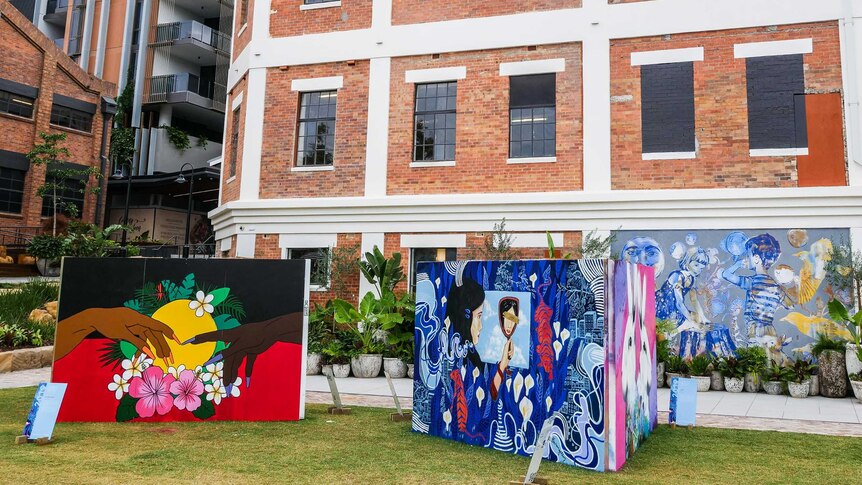 Walls of artwork in front of new and old development.