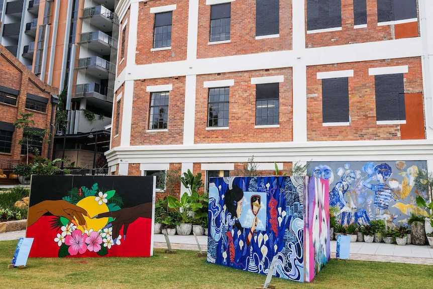Walls of artwork in front of new and old development.