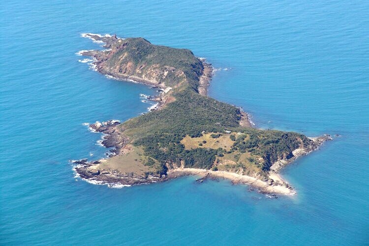 A birds eye view of a large mountainous island surrounded by turquoise water. 