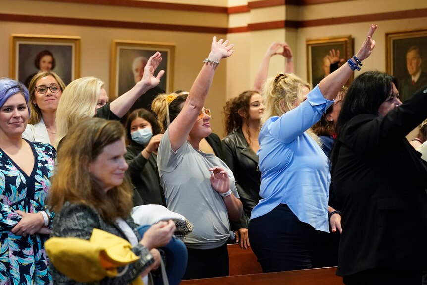 A group of women wave their hands in a court room 