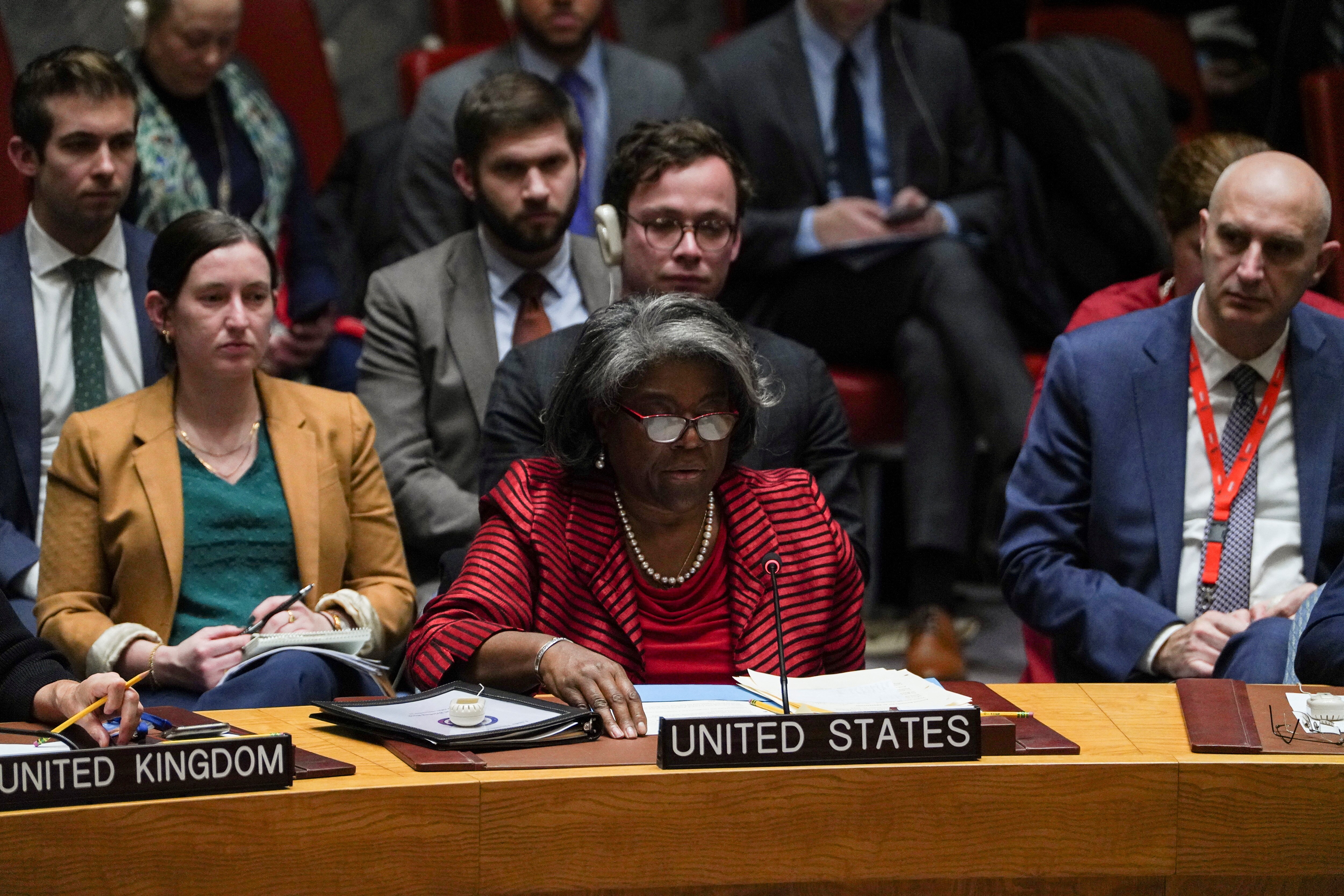 Linda Thomas-Greenfield sits at a desk, flanked by others, with a folder of documents, microphone and a 'United States' sign