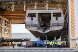 The hull of an huge ship sits inside a warehouse.