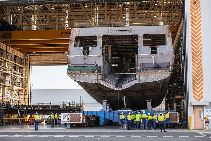 The hull of an huge ship sits inside a warehouse.