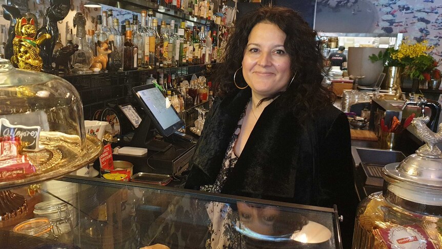 Lady standing at a bar full of drinks.