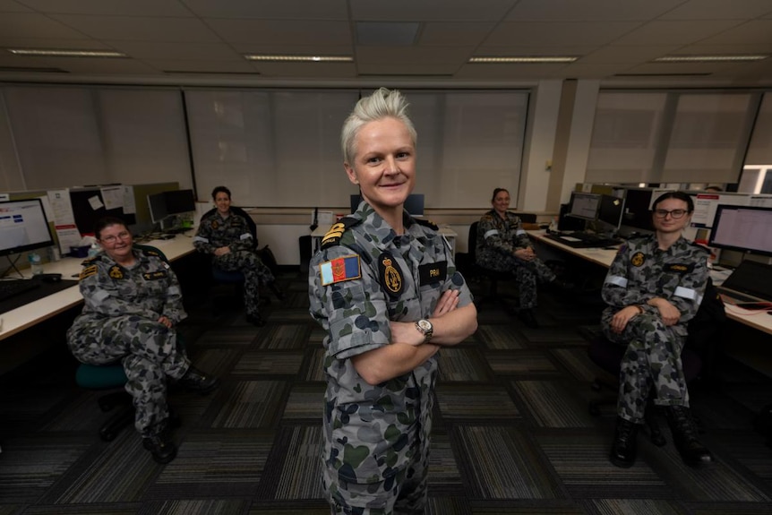 Four women in navy uniforms pose in an office