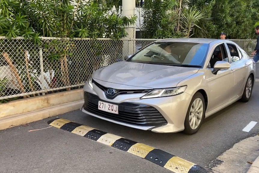 A silver car drives over a speed bump into an impound.