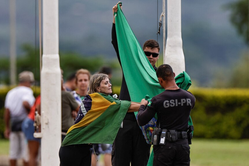 People take down the Brazilian flag from the flagpole at the Alvorada palace.