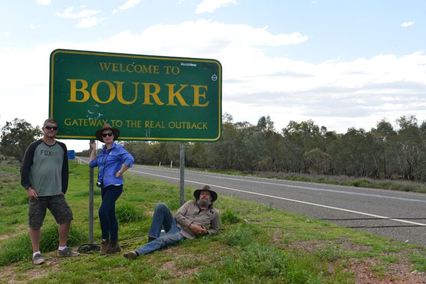 Prue Adams, Carl Saville and Tony Hill standing under Welcome to Bourke sign.