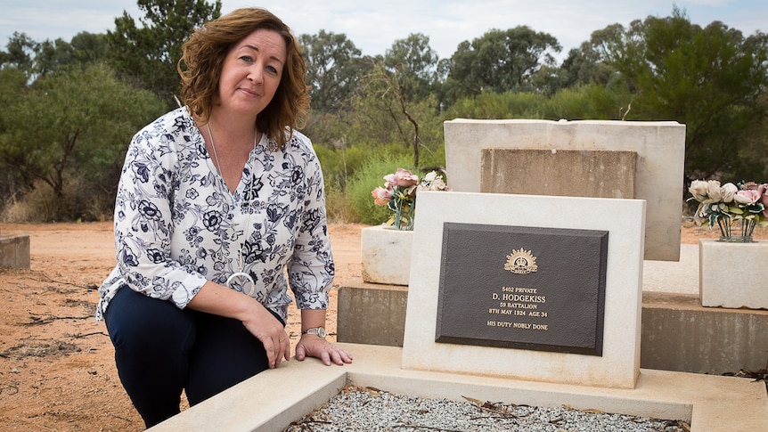 Woman sitting by a grave that was once unmarked.