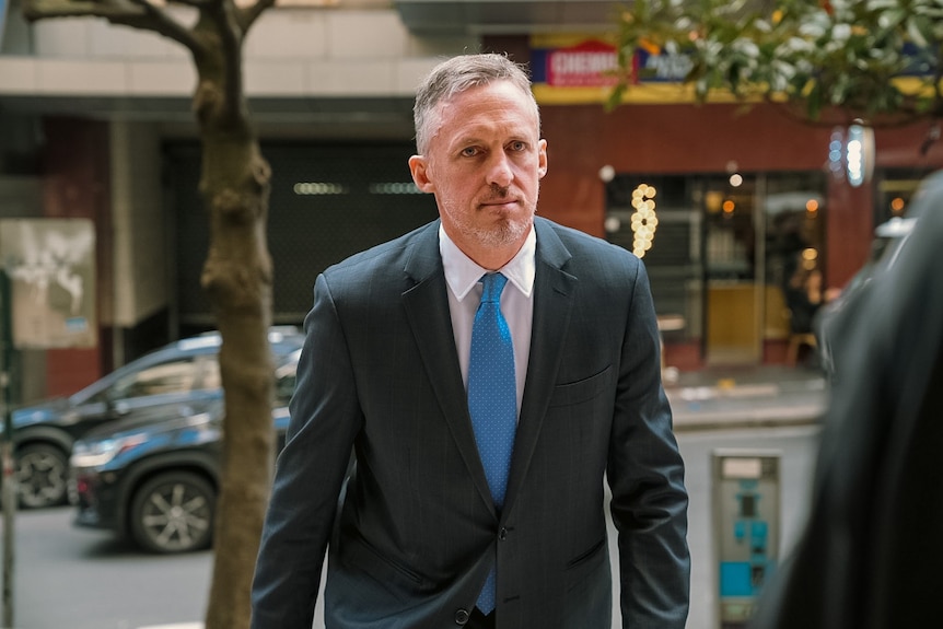 A man wearing a crisp suit stares straight ahead