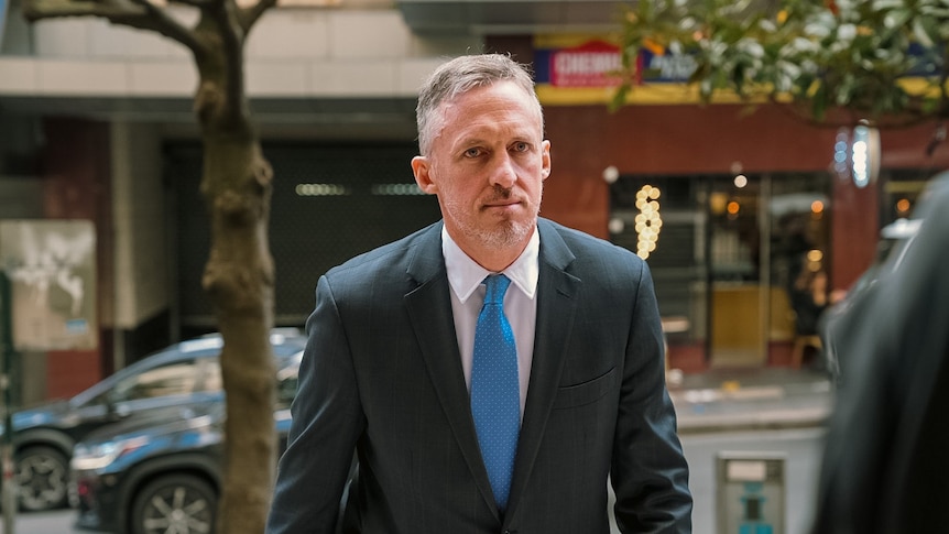 A man wearing a crisp suit stares straight ahead