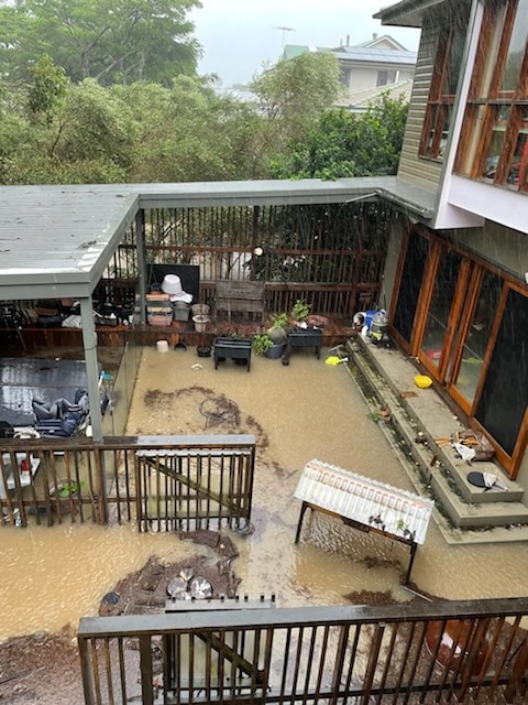 maison de Graceville pendant les inondations, avant qu'environ 1 mètre d'eau n'entre dans la maison.  Arroser à travers la cour et les marches à mi-chemin